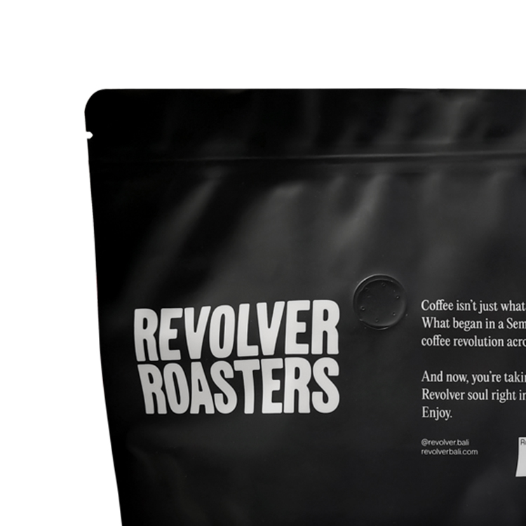 Round degassing valve on a black coffee pouch beside white artwork