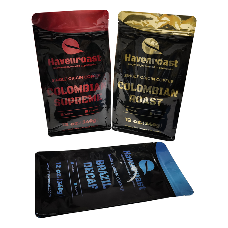 Three black coffee bags with red, gold-colored and blue printed designs arranged on a white background