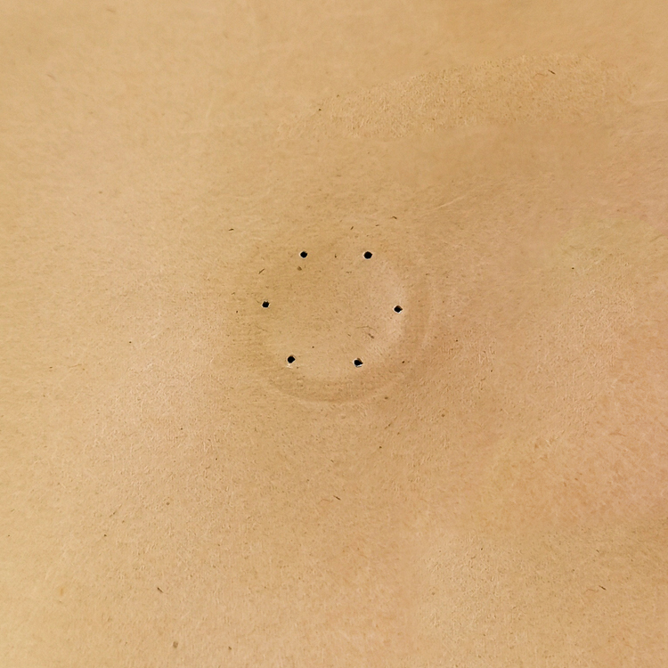 Close-up of six small openings in a brown coffee bag panel