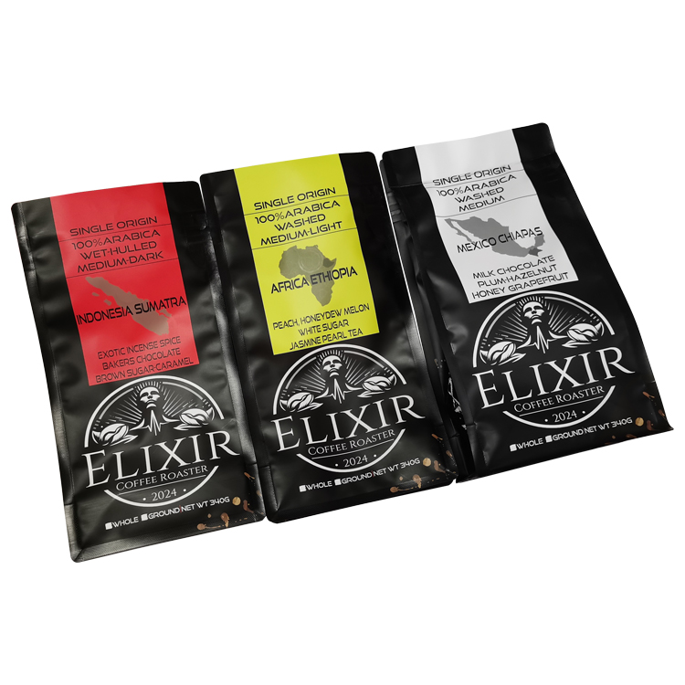 Three black coffee bags laid side by side with red, white and yellow front graphics