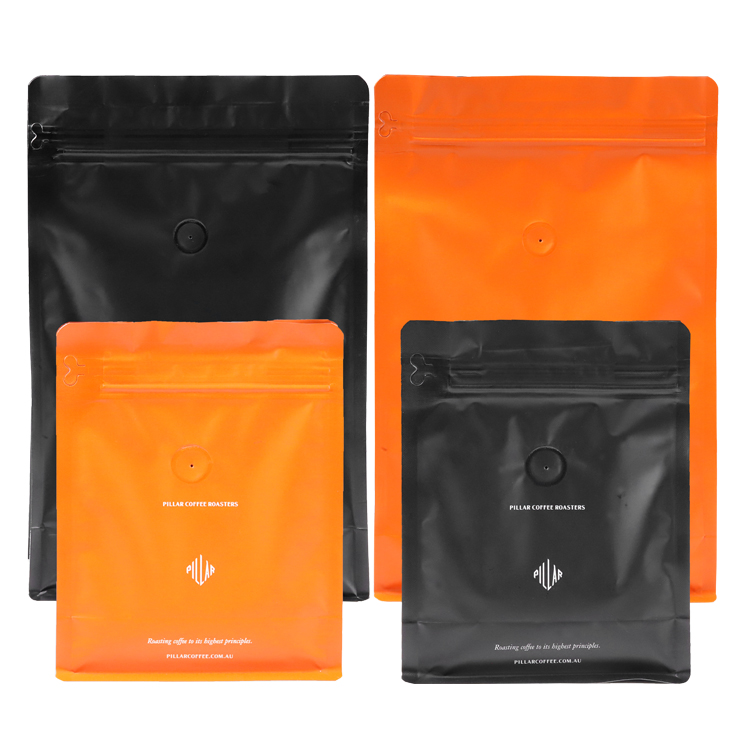 Four black and orange coffee bag views with round valves and small white brand graphics
