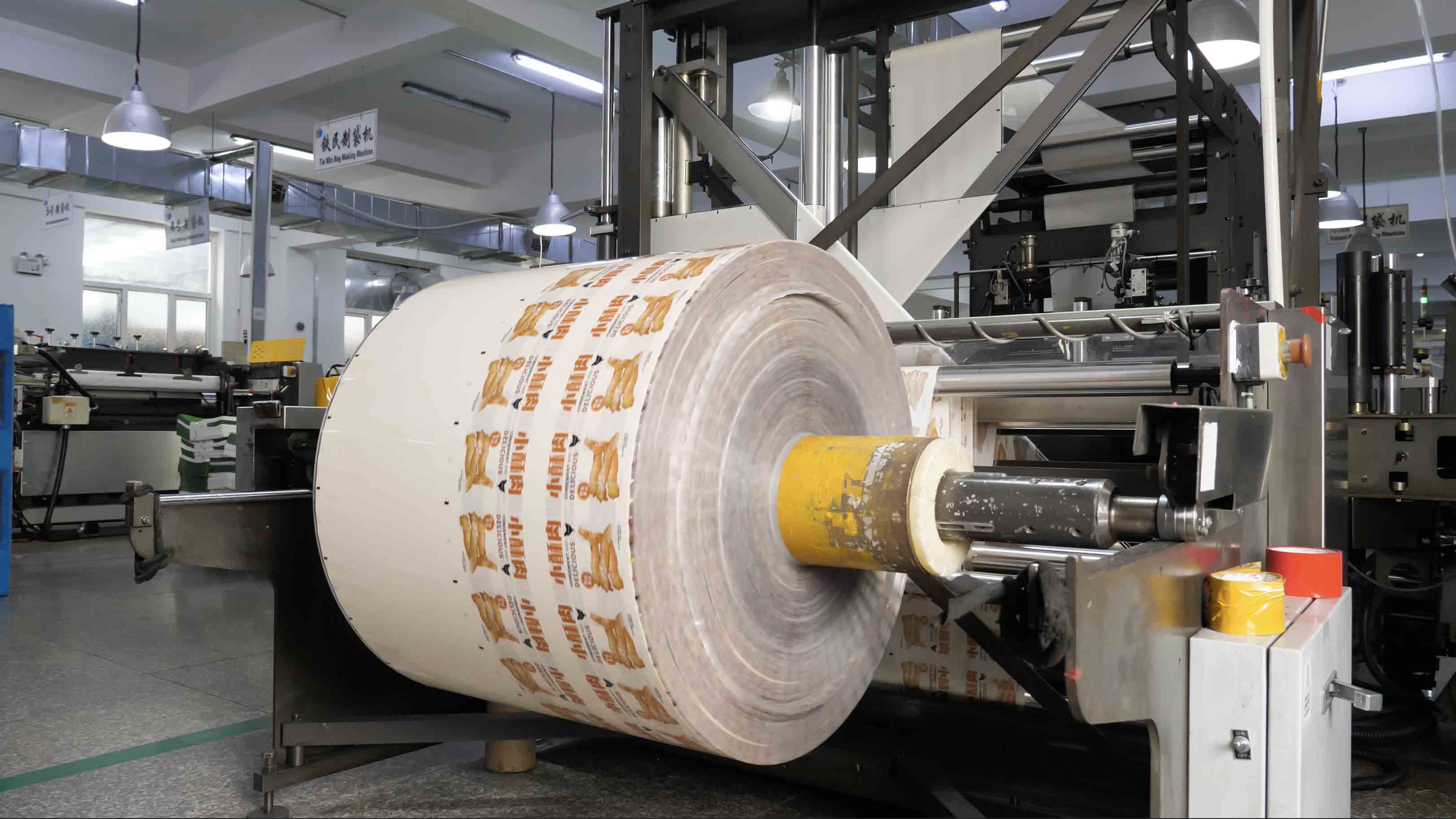 Printed packaging film wound on a roll in converting equipment