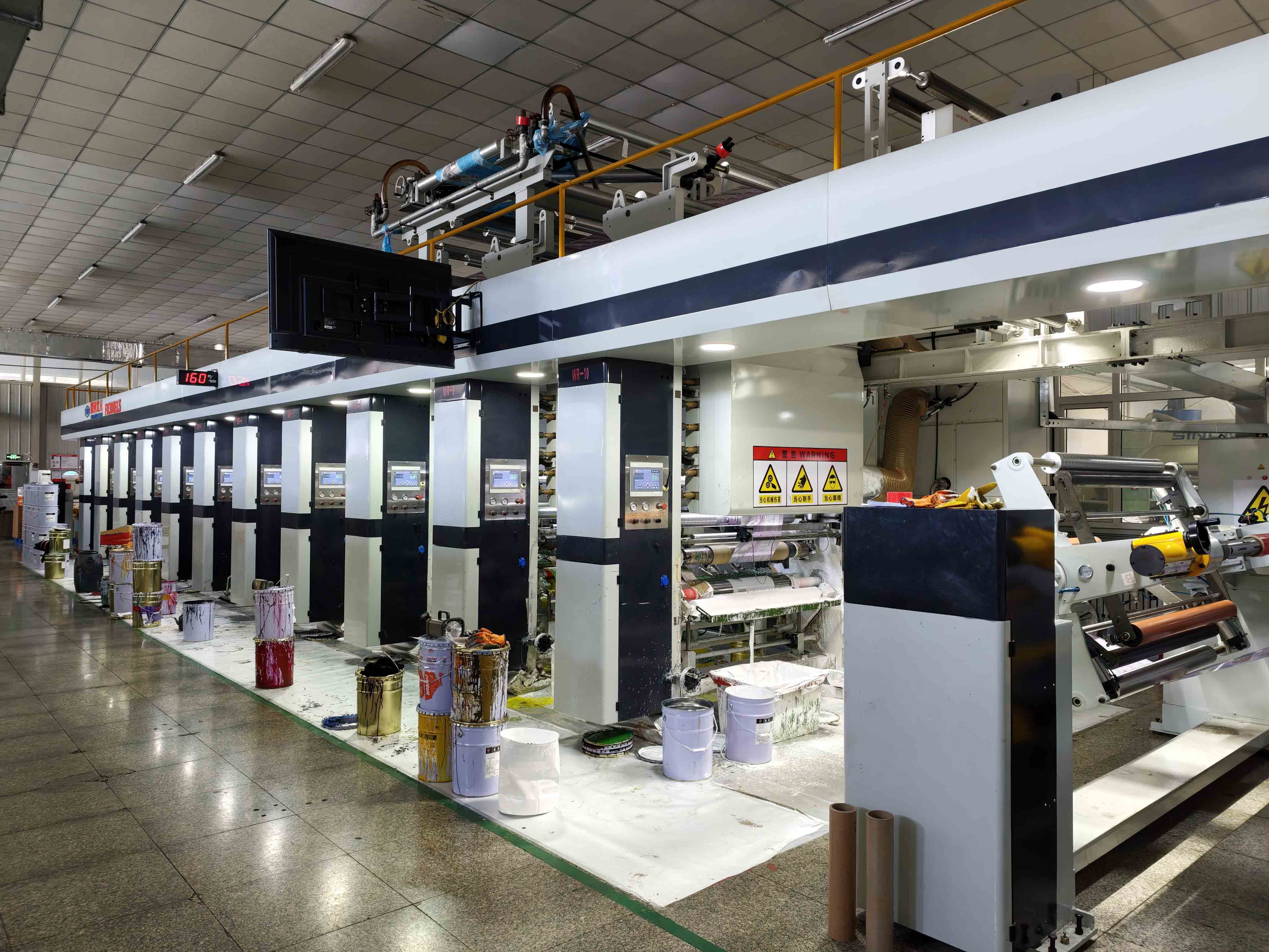 Gravure printing equipment with multiple printing units, film rollers and ink containers on the production floor