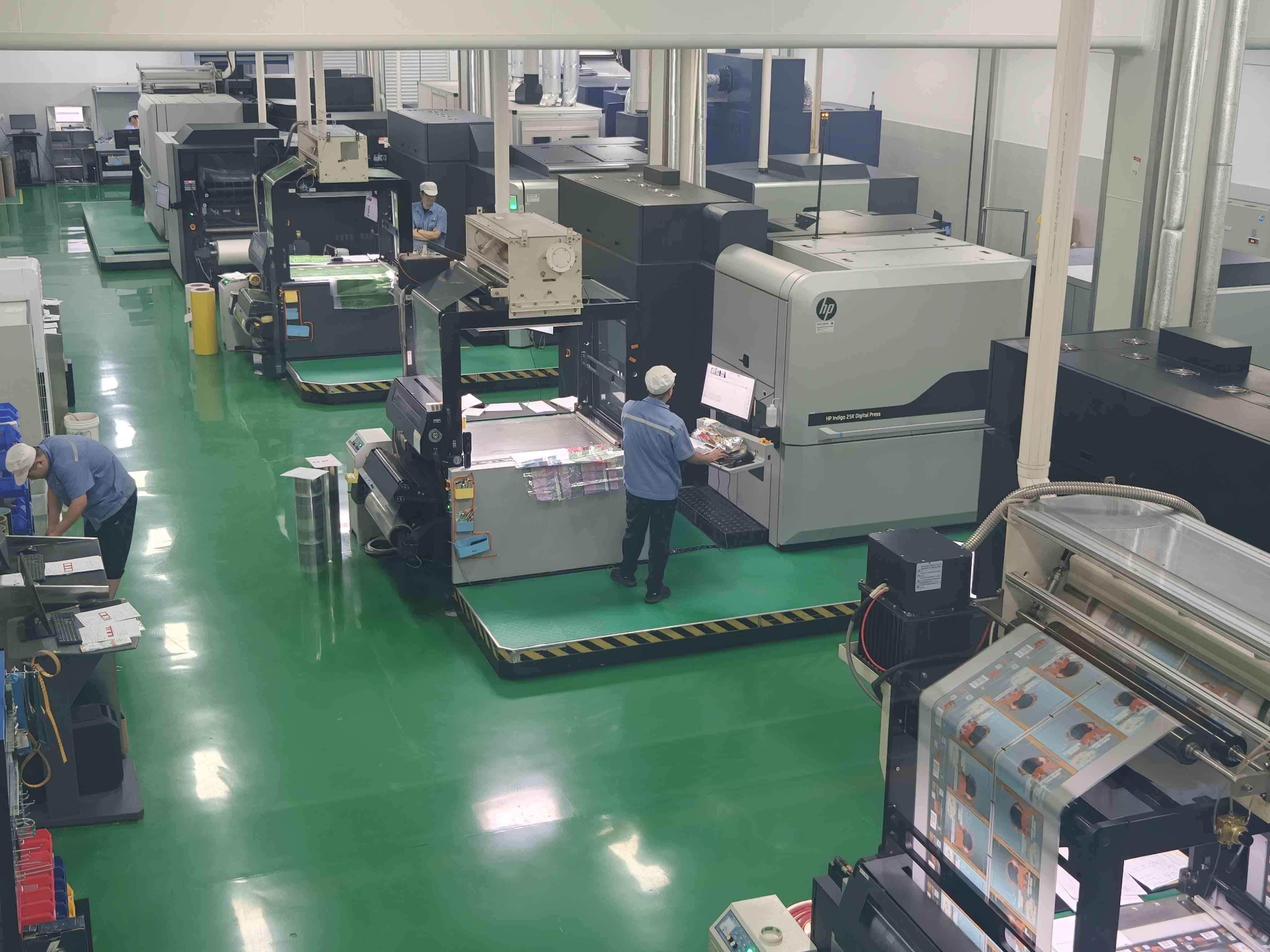 Digital printing presses and operators handling printed packaging film on the production floor