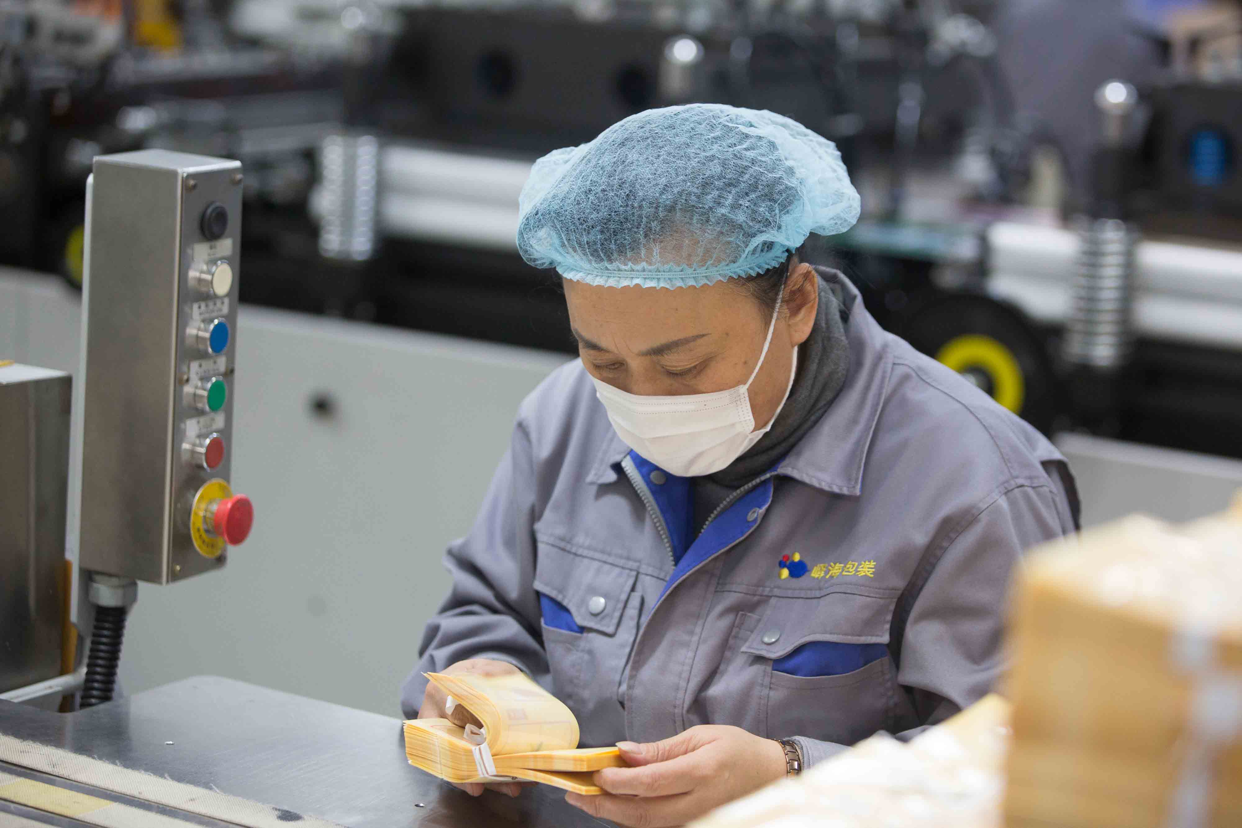 Operator handling pouches beside production equipment