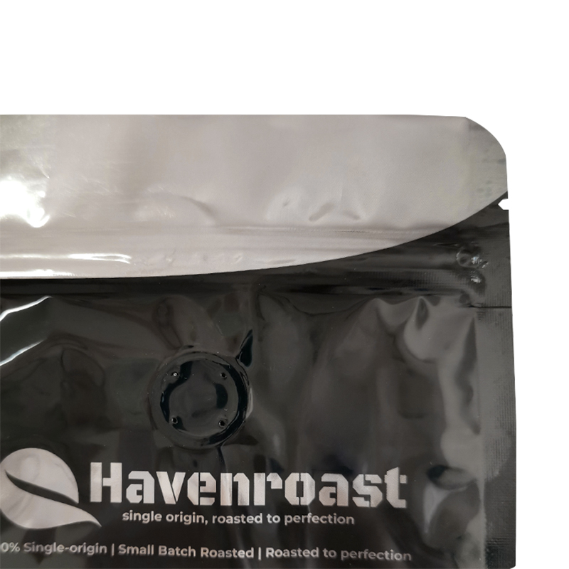 Black coffee pouch with a pale inner surface and a round valve below the opening