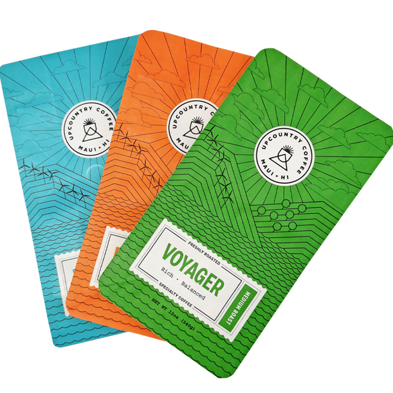 Blue, orange and green printed coffee bags overlapping on a white background